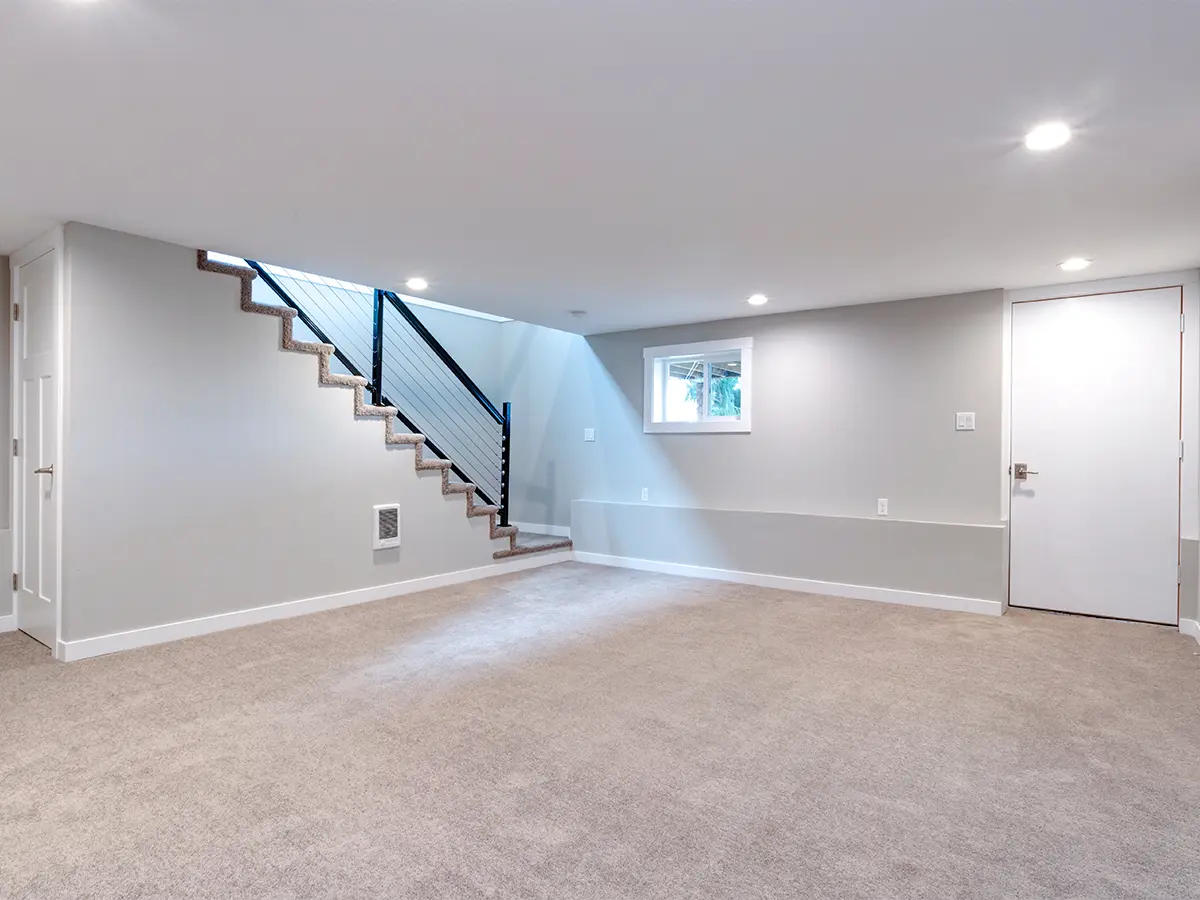 finished basement with white gray walls, spotlights, beige carpet