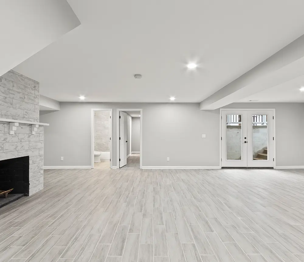 white gray remodeled basement with fireplace and spot lights