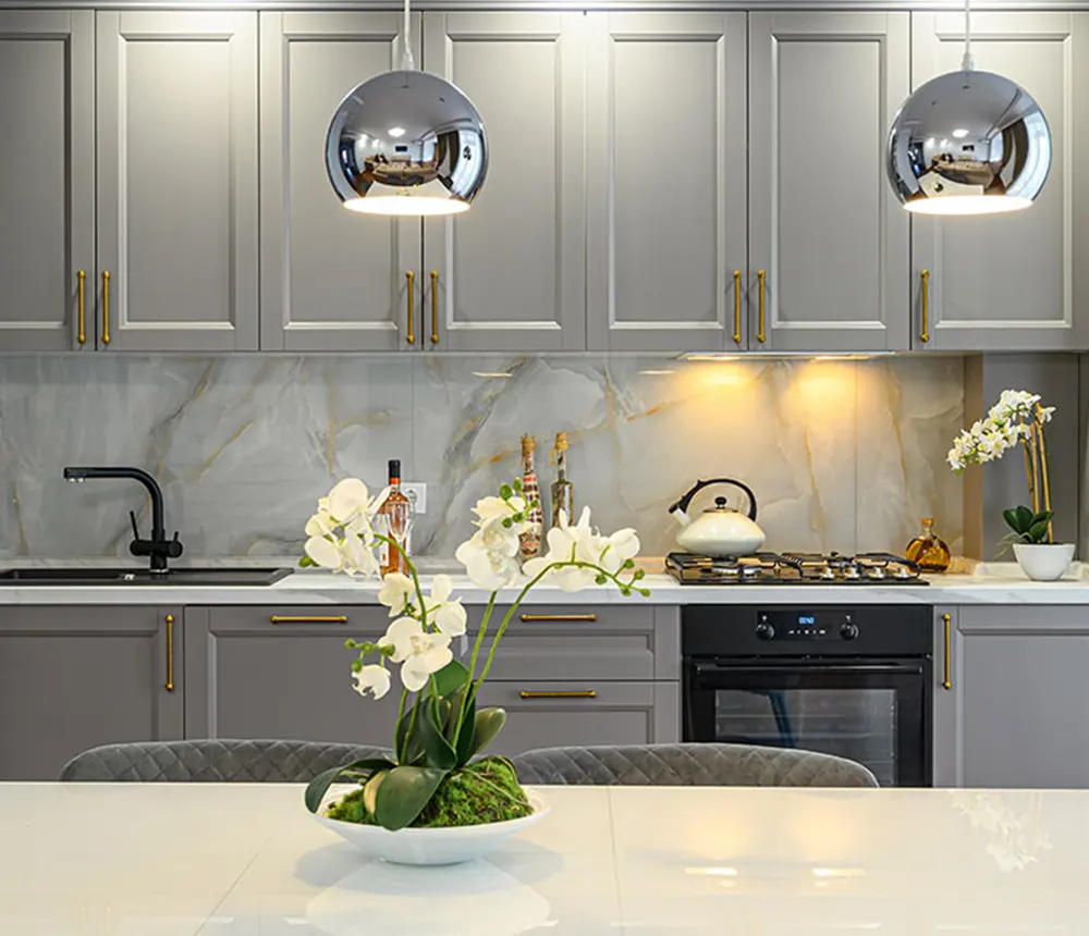 grey kitchen cabinets with golden metal handles and white marble countertop