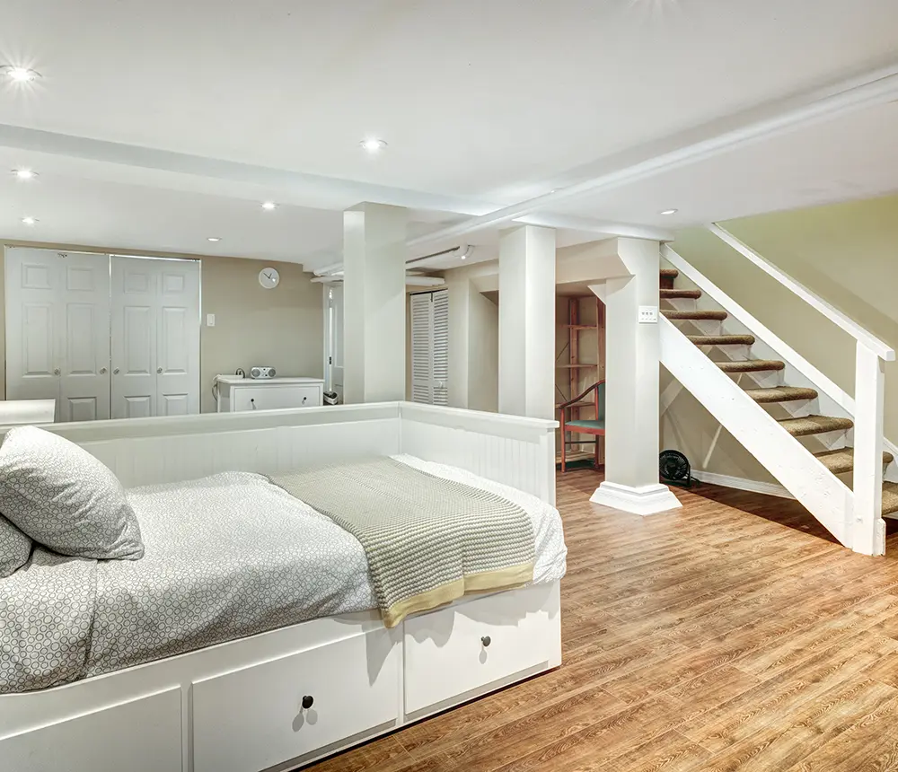 remodeled basement with wooden floor, single bed, white and cream walls